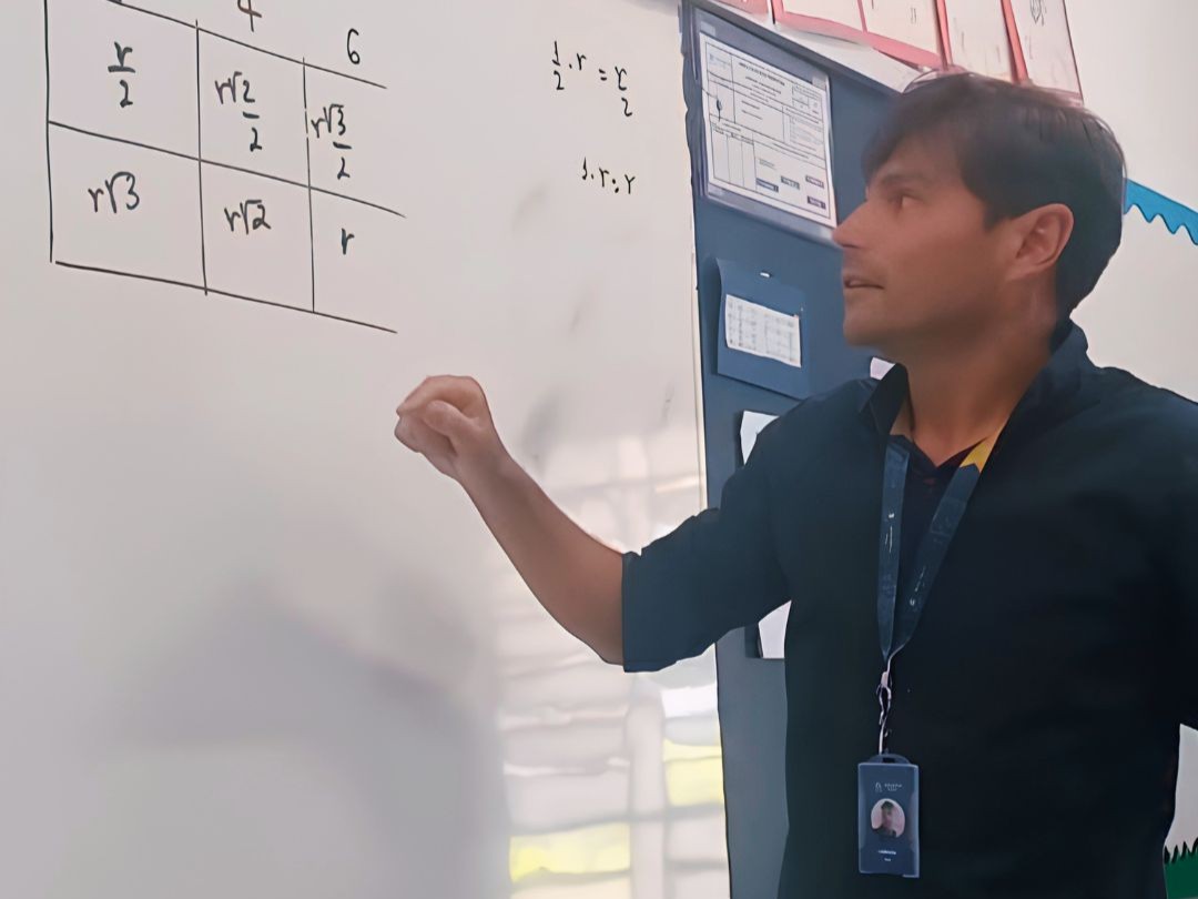 inserir aqui Professor Angelão explicando matemática no quadro branco, com equações de r e raízes, em sala de aula.